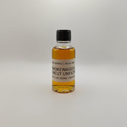 Small bottle of Smokewagon Whiskey on a white surface with a gray textured background