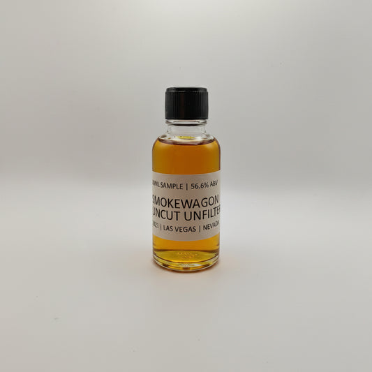 Small bottle of Smokewagon Whiskey on a white surface with a gray textured background