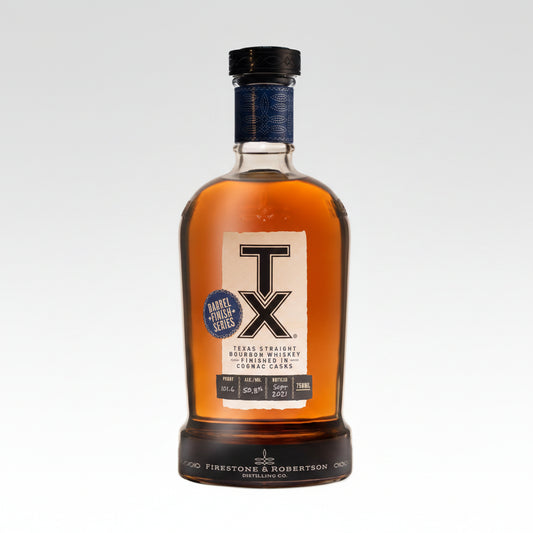 A bottle of Texas Straight Bourbon Whiskey from Firestone & Robertson Distilling Co., featuring a large white 'TX' logo on the front label, amber liquid inside a clear glass bottle, and a dark blue and black cap.