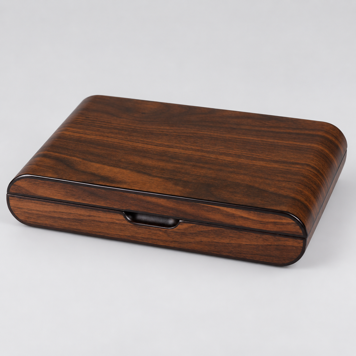 A rectangular wooden box with rounded corners, featuring a rich dark brown wood grain pattern and a glossy black trim around the front edge and a small recessed handle, shown on a light gray background.