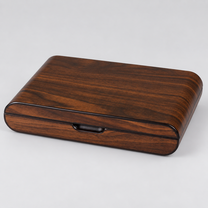A rectangular wooden box with rounded corners, featuring a rich dark brown wood grain pattern and a glossy black trim around the front edge and a small recessed handle, shown on a light gray background.