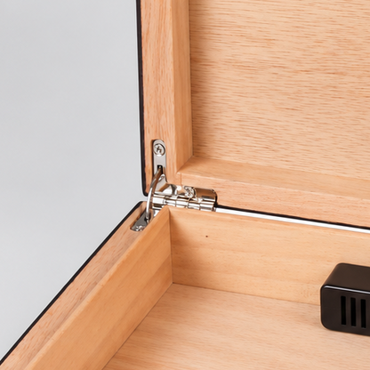 An open wooden humidor box with a light natural wood interior, dark brown wood exterior, and a small black ventilation device resting inside, shown on a light gray background.